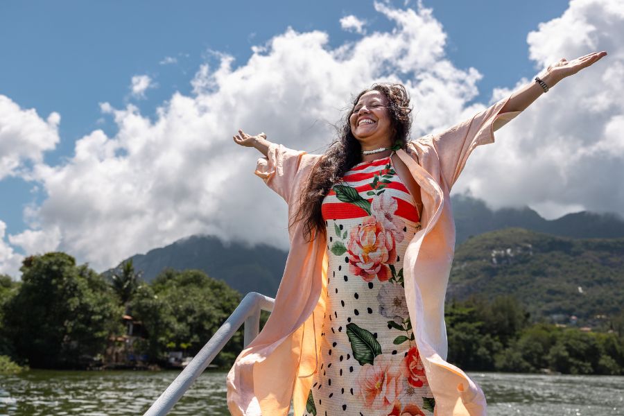 A woman with arms in the air near the ocean feeling good