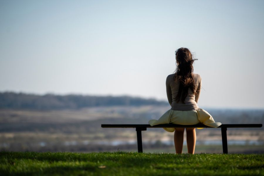 Someone sitting on a bench looking reflective