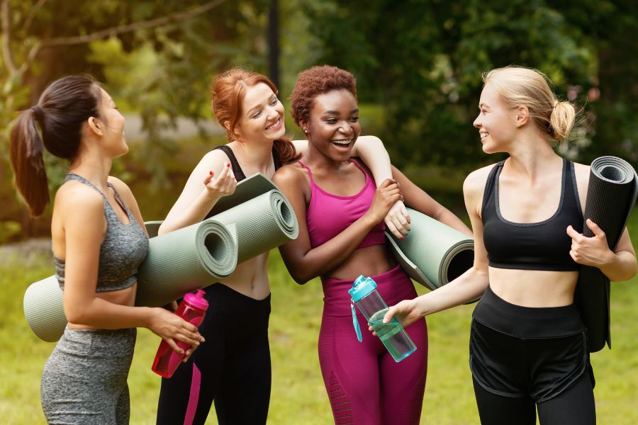 Women laughing together before yoga in the park