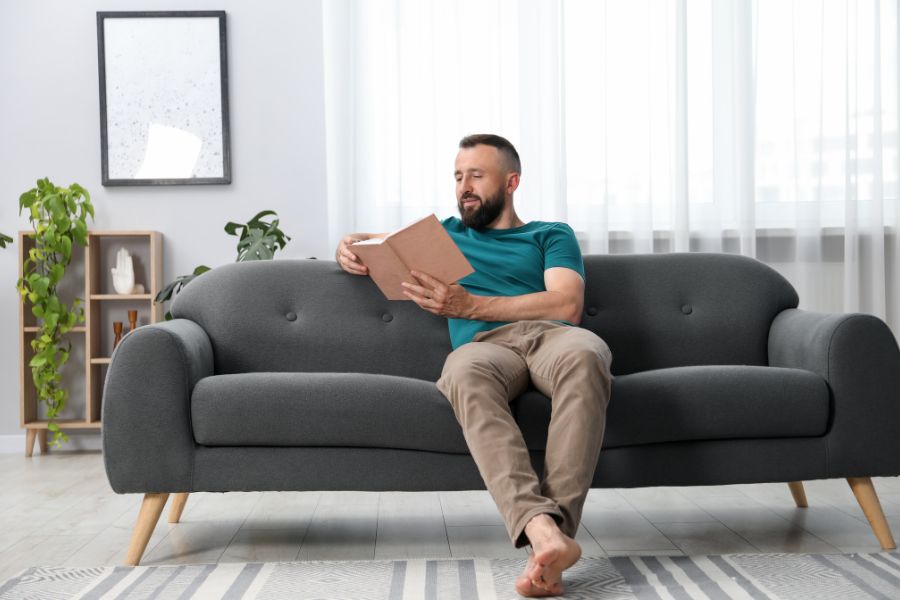 person resting on a couch reading a book